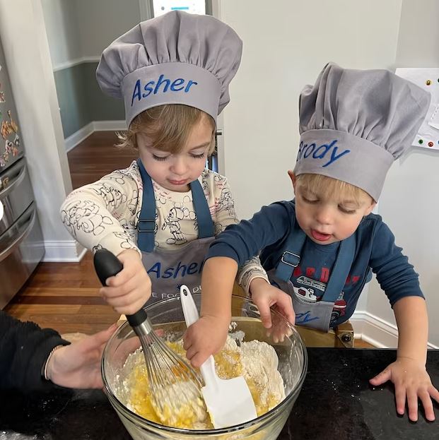 Toddler boy wearing personalized gray apron and chef hat with embroidered name – kids cooking gift set