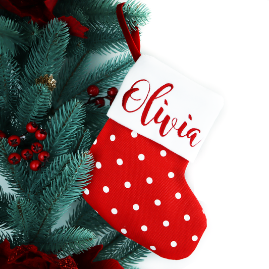Stocking with the name Olivia hanging among pine branches and red berries