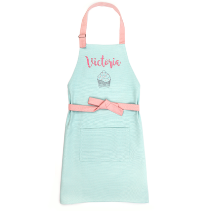Personalized mint green apron on a white background, embroidered with the name "Victoria" above a cupcake outline design