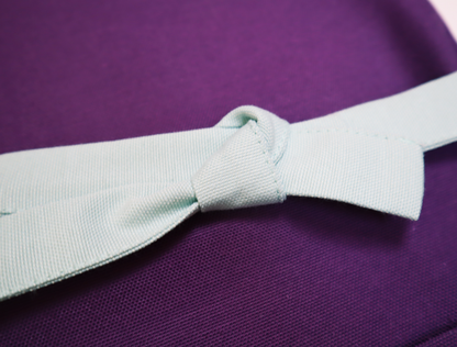 Close-up of a mint-colored strap tied in a knot on a personalized purple apron