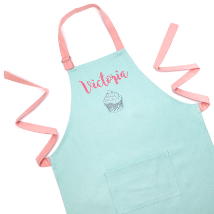 Personalized mint green apron with pink straps, embroidered with the name "Victoria" above a cupcake icon