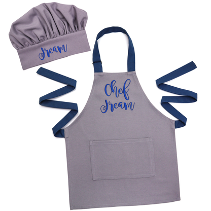 Personalized grey apron and chef hat set with navy straps, embroidered "Chef Dream", on a white background