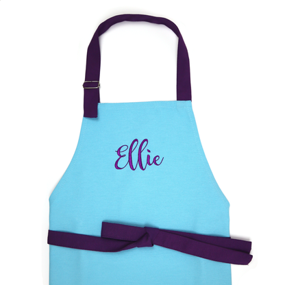 Personalized turquoise blue kids apron with purple straps, embroidered with the name "Ellie" in cursive, on a white background