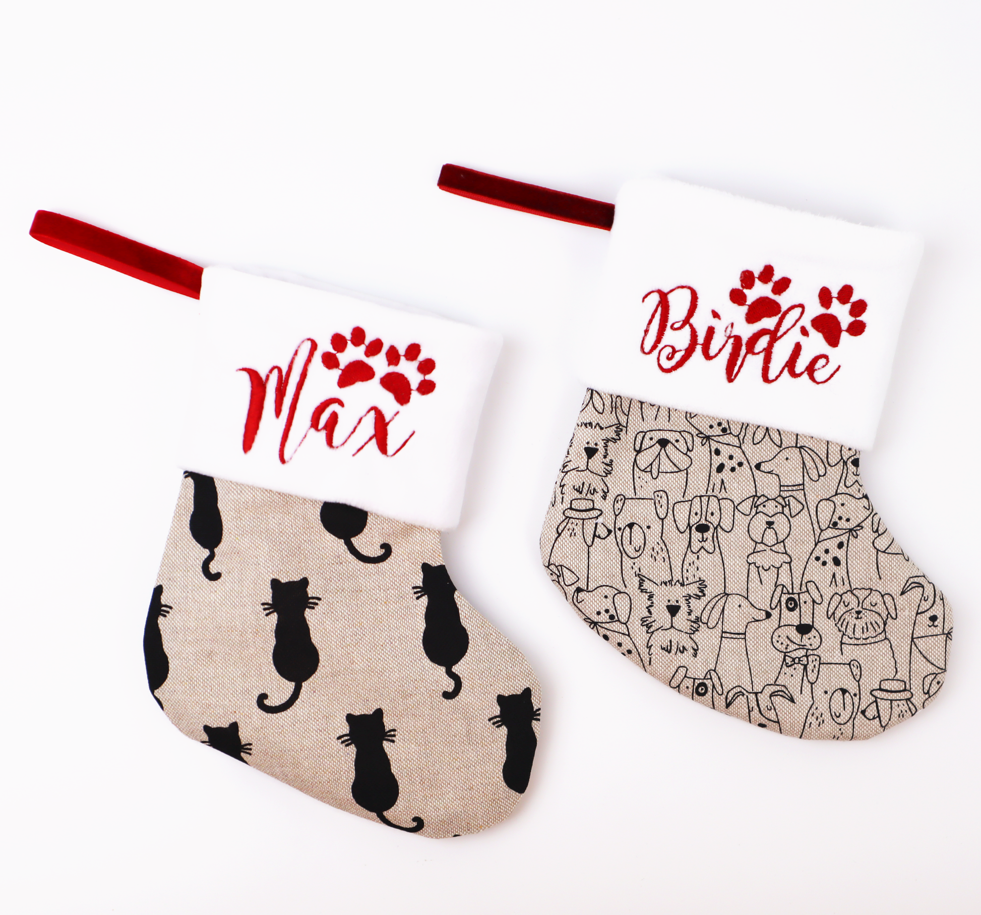 Two mini linen Christmas stockings side by side, one with a dog print and one with a cat print, embroidered with the names Birdie and Max in red