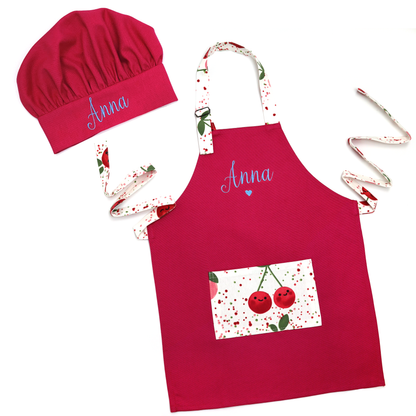 Personalized hot pink apron and matching chef hat set with cherry-print trim, embroidered with the name "Addie"