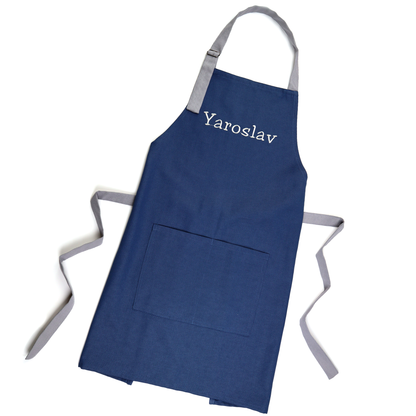 Personalized navy apron on a wooden hanger, embroidered with the name "Yaroslav"
