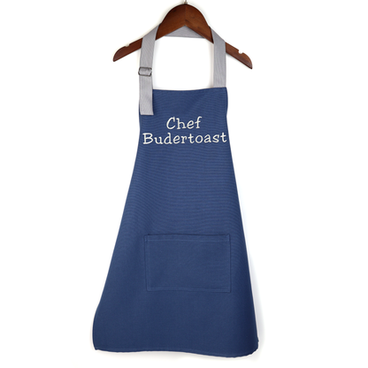 Personalized navy apron on a wooden hanger, embroidered with a chef name design