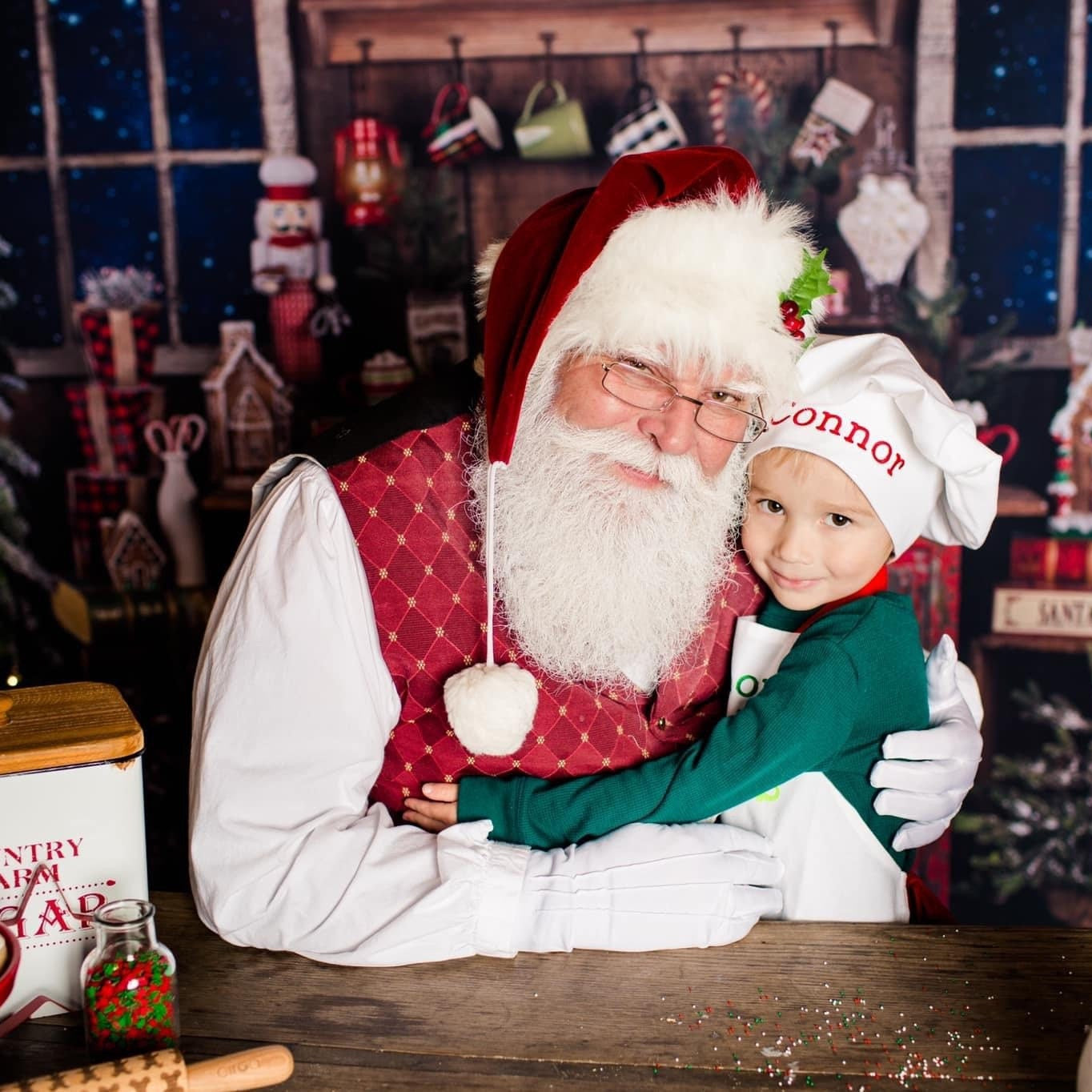Santa Claus hugging a child wearing personalized christmas apron with pockets with Christmas decorations.