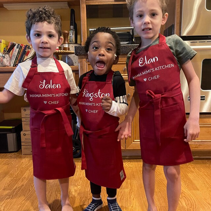 Three children wearing matching personalized dark red aprons, standing together