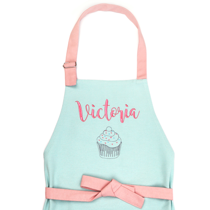 Personalized mint green apron with coral straps, embroidered with the name "Victoria" above a cupcake outline design