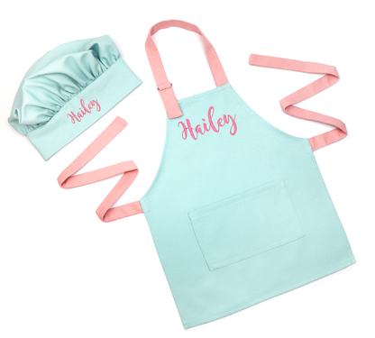 Personalized mint green apron and chef hat set with pink straps, embroidered with the name "Hailey" in pink cursive, on a white background